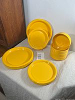 Full view of set with large plates, smaller plates, and bowls stacked, showing vibrant yellow color on cloth surface.