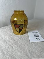 Amber glass light shade showing shape and shield motif on front.