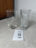 Clear glass vintage Canadian Club highball glass with white logo and wave pattern design, 6.5 inches tall, shown on table near the pitcher.