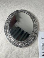 Top view of vintage sterling silver framed oval mirror with ornate decorative border