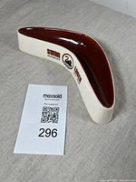 Angled front view of boomerang-shaped ceramic ash tray showing Swan Lager branding and brown interior.