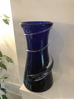 Front view of a tall cobalt blue glass vase with a clear spiral swirl wrapping around the exterior body, showing shape and color.