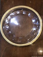 Full view of the large round glass plate showing its transparent body and detailed gold rim decoration.