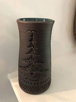 Front view of the pottery vase showing the carved Tree of Peace design topped with an eagle and the textured base pattern.