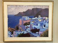 Full view of the oil painting with gold frame showing a Greek coastal landscape scene with pastel buildings and sea.