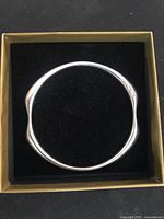 Overhead view of wave-form bangle on black velvet inside gold-toned display box