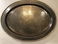 Full view of the vintage oval brass tray showing the hammered and engraved patterns with an aged patina.