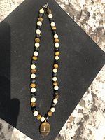 Full view of the necklace showing the stone beads and large tiger eye pendant.