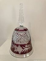 Front view of red crystal glass bell with floral etching and diamond cut detailing