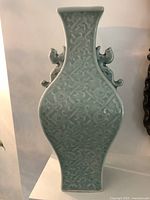 Front view of celadon green vase showing detailed embossed pattern and side handles.
