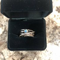 Front view of vintage sterling silver ring with blue opal stone displayed in black jewelry box on marble surface.