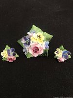 Front view of the vintage Radnor fine bone china flower bouquet brooch and matching earrings, showing pastel flower details and green leaves.