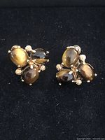 Front view of the pair of vintage napier earrings showing tiger eye cabochon stones set in gold-tone metal with decorative bead accents.