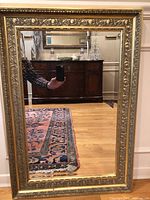 Front view of vintage gold ornate framed mirror showing full mirror and frame.