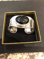 Top and angled view of the vintage sterling silver cuff bracelet featuring a large oval black chalcedony stone set on a wide, polished silver band.