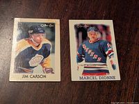 Front of two 1987-88 O-Pee-Chee NHL hockey cards showing Jimmy Carson in Toronto Maple Leafs jersey and Marcel Dionne in New York Rangers jersey.