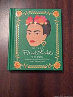 Front cover of the Pocket Frida Kahlo Wisdom hardcover book showing an illustration of Frida Kahlo with flowers, green background, and decorative border.