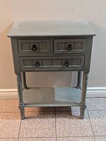 Front view of the antique grey console table showing the three drawers with ring pull handles and lower shelf.