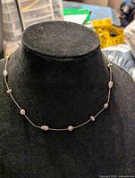 Front view of Monet silver tone wire choker necklace with pearl beads spaced along the wire, displayed on black velvet bust.