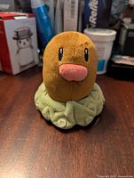 Front view of the brown Diglett Pokemon plush toy, showing face and green base.