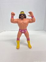 Front view of Macho Man Randy Savage LJN action figure standing with arms flexed, showing facial features, headband, and detailed paint on trunks and boots.