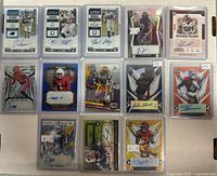 View of 14 assorted autographed football cards laid out on a flat surface, including rookie tickets, Prizm, and Rising Stock cards