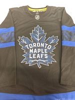 Front view of black Toronto Maple Leafs hockey jersey showing logo and sleeves.