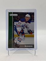 Front side of Connor McDavid rookie card from 2015-16 Upper Deck Series One Parkhurst set displayed in a protective holder on a stand.