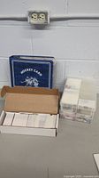 Overall view of the hockey card lot showing a blue binder, a cardboard box with loose cards, and plastic container storage with hockey cards.