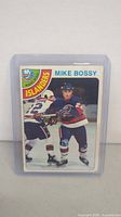 Front of 1978-79 O-Pee-Chee Mike Bossy rookie card showing player image and team logo with card number 115.