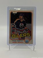 Front of 1981 O-Pee-Chee Paul Coffey rookie hockey card showing player photo, team logos, and bright orange borders.