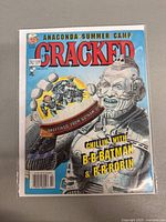 Front cover of Cracked magazine issue 320, shows a robotic character holding a snow globe featuring Batman and Robin and text about Gotham City.