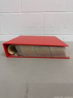 Side view of red three-ring binder filled with trading card pages