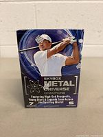 Front view of sealed Skybox Metal Universe Champions card box featuring a golfer in white attire swinging a golf club.