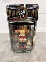 Front view of Ken Shamrock WWE Classic Superstars action figure in original package with autograph on plastic display and accessories inside.