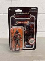 Front view of the Star Wars The Mandalorian action figure packaged, showing character and accessories inside blister pack with card backing.