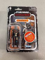 Front view of the packaged Star Wars The Mandalorian action figure showing the figure and accessories inside clear plastic blister with cardboard backing featuring the character and Retro Collection sticker.