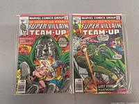 Two vintage Marvel Super-Villain Team-Up comic books in protective sleeves, showing full front covers of issues #11 and #13.