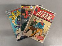 Front view of three comic books in plastic sleeves, two Joker issues and one Superman's Pal Jimmy Olsen issue.