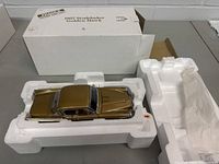 Top angled view of the vintage die cast car in styrofoam packaging, showing metallic gold paint and box details.