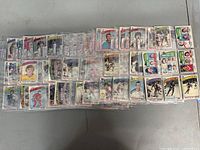 Photo shows a wide layout of various 1975 NHL O-Pee-Chee hockey cards in protective sleeves on a flat surface. Multiple teams and players visible.