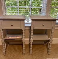 Front view of two matching gray bedside tables showing drawer and bookshelf area with magazines.