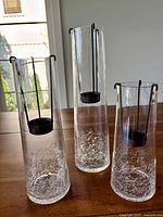 Set of 3 clear crackle glass votive candle holders on wooden surface with sunlight coming through a window.
