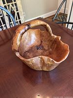 Top angle view of hand carved wooden burl bowl displaying wood grain and handle.