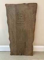 Single carved wood wall hanging with intricate geometric carvings in natural wood tone