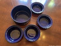 Large cobalt blue soufflé dish with four smaller matching bowls arranged on wooden table.