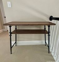 Front view of console table showing wood top and shelf with black metal legs and frame