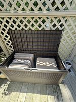 Open deck box with multiple seat cushions stored inside, showing interior size and condition.