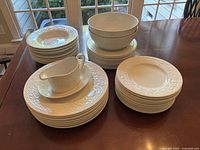 Stacks of plates, bowls, gravy boat and saucer arranged on wooden table under window