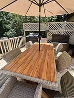 Overhead diagonal view of rectangular teak tabletop and resin wicker chairs with umbrella inserted